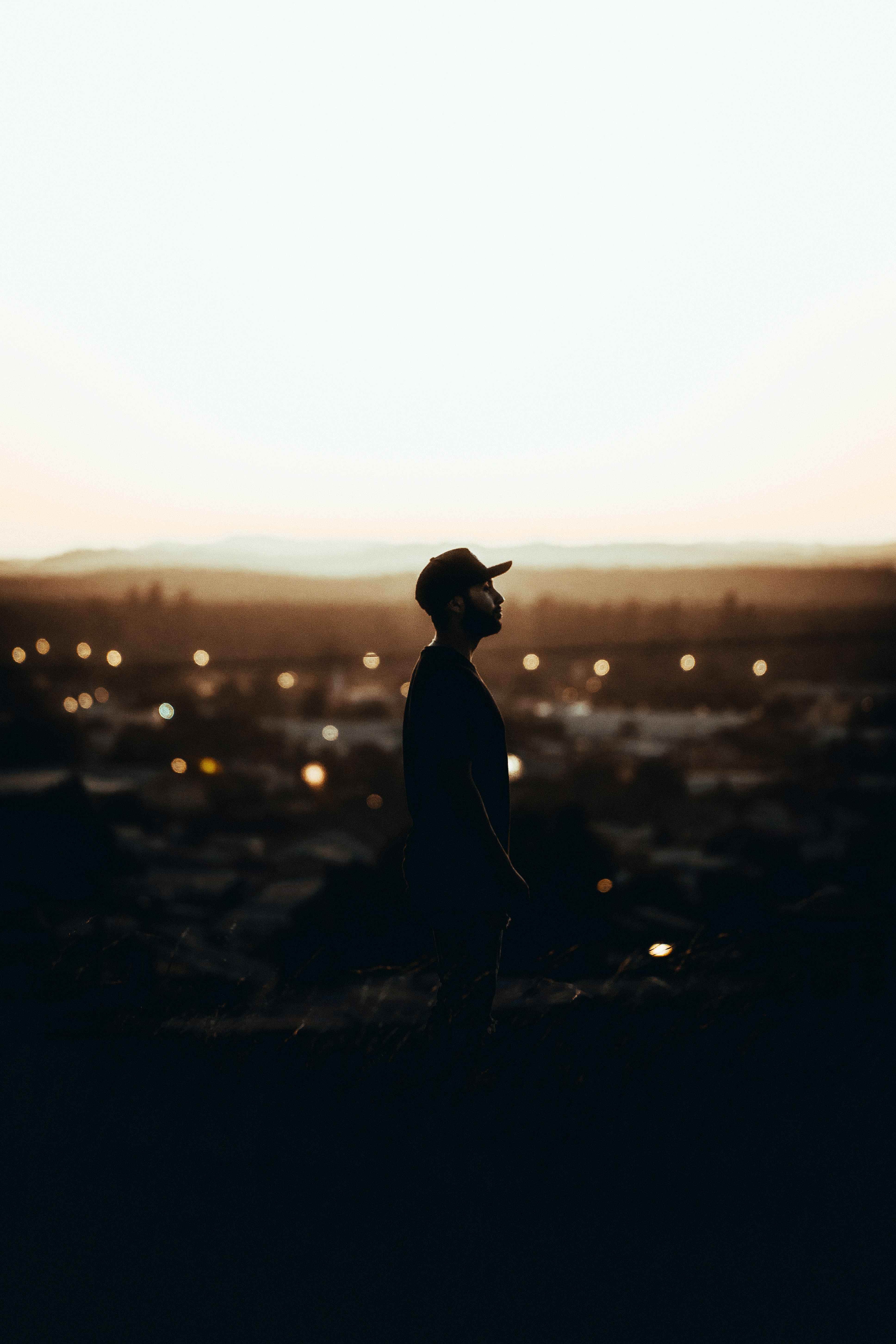 silhouette of man wearing hat standing on ground during sunset